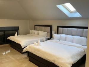 - une chambre avec 2 lits avec des draps blancs et une lucarne dans l'établissement Mizirawi Historic Hotel, à Ramallah