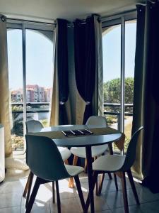 een tafel en stoelen in een kamer met een raam bij Vue INCROYABLE sur le Lac, détente assurée ! café de bienvenue offert in Le Barcarès