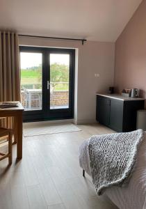 a bedroom with a bed and a kitchen with a window at B&B Aasterbergerhoeve in Echt