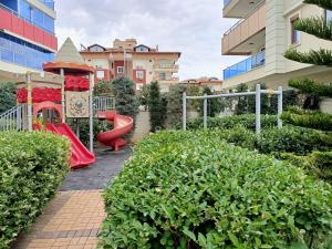 un parque infantil con un tobogán rojo y una estructura de juegos en 2-Room Accommodation in a Luxury Resort, en Alanya