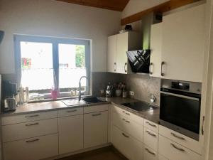 a kitchen with white cabinets and a sink and a window at Wiehler- Ferienwohnung in Wiehl