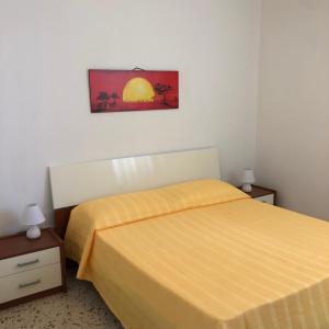 a bedroom with a yellow bed and two night stands at Residence Arcobaleno in San Vito lo Capo