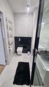 a white bathroom with a toilet and a sink at APARTAMENT De Lux Parkowa Olecko in Olecko +22 photos