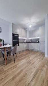 a kitchen with white cabinets and a table and a chair at APARTAMENT De Lux Parkowa Olecko in Olecko