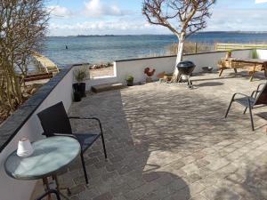 a patio with chairs and a grill and the water at Strand Huset in Faaborg