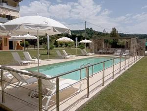 a pool with chairs and umbrellas next to a house at Alex House in Zakharo