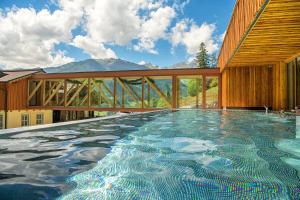 a swimming pool in front of a building with a mountain at Berghotel Hauserbauer in Dorfgastein