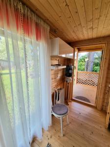 a room with a window and a chair in a tiny house at Piejūras namiņš in Kolka