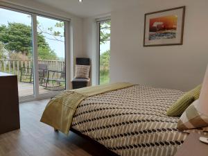 a bedroom with a large bed and a balcony at Bayview Lodge New Spacious Apartment in Breakish