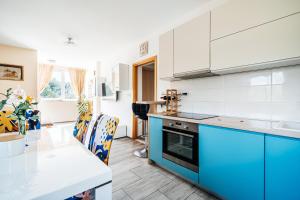 a kitchen with blue and white cabinets and a table at Green Hill Apartment in Komaji
