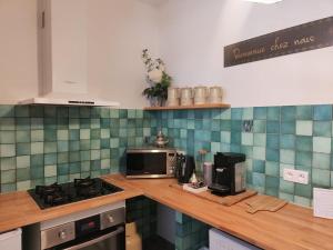 una cocina con azulejos verdes y azules en la pared en L'Empire D'Essences Appartement, en Valréas