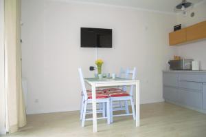 a kitchen with a table and two chairs and a tv at Magic Marine Apartment in Dziwnówek