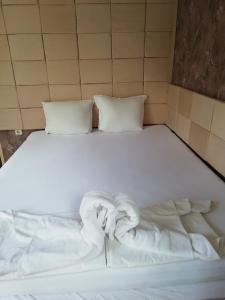 a white bed with two pillows and towels on it at Guest House Ivy in Ravda