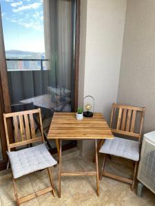 a wooden table and two chairs in a room with a window at City view in Residences in Burgas City