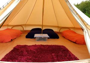 a tent with two pillows and a red rug at Glamping in the Kent weald nr Tenterden Spacious quite site up to 6 equipped tents, each group has their own facilities Tranquil and beautiful rural location yet just an hour to London in Tenterden