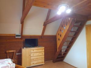 a bedroom with a staircase and a bed and a television at Őzike Apartmanházak in Bogács