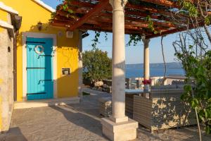 a yellow and blue house with a blue door at Olive Trees Cottage in Bol