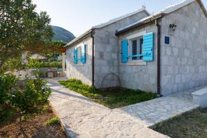 a stone house with blue shutters and a patio at Olive Trees Cottage in Bol