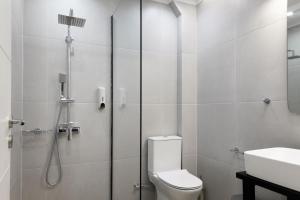a bathroom with a shower and a toilet and a sink at Corali Suites Andros in Batsi +57 photos