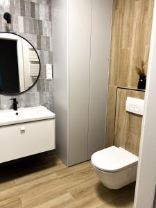 La salle de bains est pourvue de toilettes blanches et d'un miroir. dans l'établissement Apartament Polanki Aqua A408, à Kołobrzeg