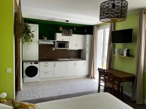 a kitchen with green walls and white cabinets and a table at ver(t) chez nous in Périgueux