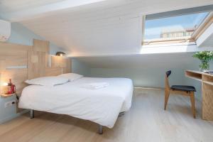 a bedroom with a white bed and a window at La Mansarde du Port HOME STAY in Nice