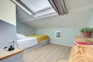 a attic bedroom with a bed and a skylight at La Mansarde du Port HOME STAY in Nice