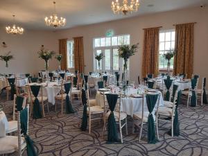 una sala de banquetes con mesas, sillas y lámparas de araña en The Judds Folly Hotel, Sure Hotel Collection by Best Western, en Faversham