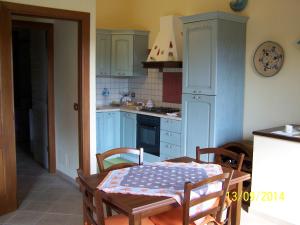 cocina con armarios azules, mesa y sillas en Villa Julia, en Tertenìa