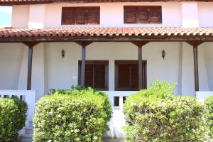 Casa blanca con ventanas con persianas marrones y arbustos en Candia House, en Kandia