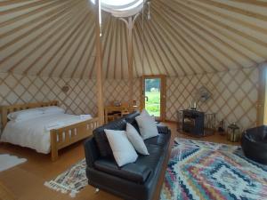 a bedroom with a bed and a couch in a yurt at Embrace the Space in Cwm-Morgan