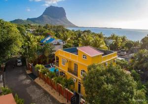 a yellow house with a mountain in the background at Lukshvilla private villa Le morne wind n kite surfers accomodation & car rental mauritius in La Gaulette