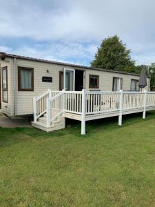 a mobile home with a porch and a white fence at Norfolk Caravan Staycation Pet Friendly in Belton