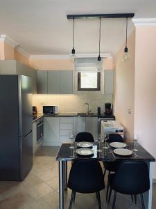 a kitchen with a table with chairs and a refrigerator at Seaside "Stone & Light Villa II" close to Aegina City in Khlóï