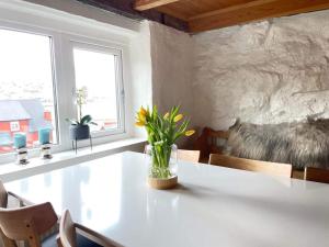 un jarrón de flores sentado en una mesa en una habitación en Abbasa hús-Grandpa s house Kumlavegur 9, en Miðvágur