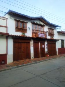 ein weißes Haus mit Holztüren und einem Balkon in der Unterkunft La Casa de Mamá Tere in Zapatoca