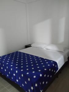 a bed with a blue blanket with white stars on it at La Casa de Mamá Tere in Zapatoca