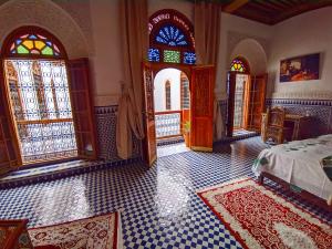 een slaapkamer met een bed en glas-in-loodramen bij Riad Fès Center in Fès