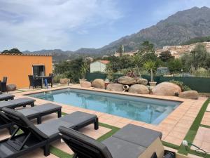 a swimming pool with chaise lounges and chairs around it at A CASA DI JO in Calenzana