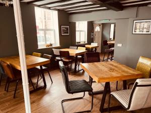 um restaurante com mesas e cadeiras de madeira e janelas em Severn Valley Guest House em Bewdley