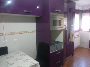 a kitchen with a purple wall with a microwave at Keymar in San Miguel de Meruelo