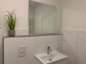 Un baño blanco con lavabo y espejo. en Haus-Marina, en Rantum 19 fotos más