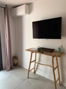 drewniany stół z telewizorem z płaskim ekranem na ścianie w obiekcie Chambres d’hôtes Casarena w mieście Porto-Vecchio