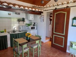una cucina con tavolo e sedie e una cucina con lavandino di Casinha de campo- Quintinha dos Cavalos- Arruda dos Vinhos ad Arruda dos Vinhos