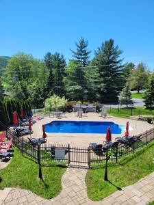 a swimming pool with people sitting in chairs around it at Condo 202 Le Champlain vue sur la montagne, ski, vélo, piscine ! in Bromont