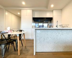 een keuken met witte kasten en een tafel en stoelen bij Readyset Apartments at Marque in Melbourne