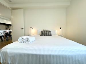 een slaapkamer met een groot wit bed en handdoeken bij Readyset Apartments at Marque in Melbourne