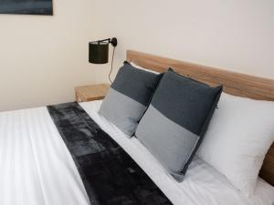 a bed with three pillows on it in a bedroom at Inala Hotel in Brisbane