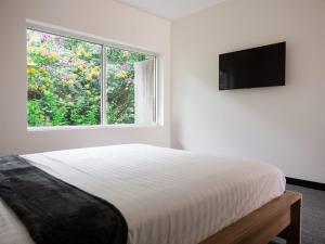 a white bedroom with a bed and a window at Inala Hotel in Brisbane