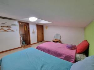 a bedroom with two beds and a mirror at Tongyeong One Guesthouse in Tongyeong